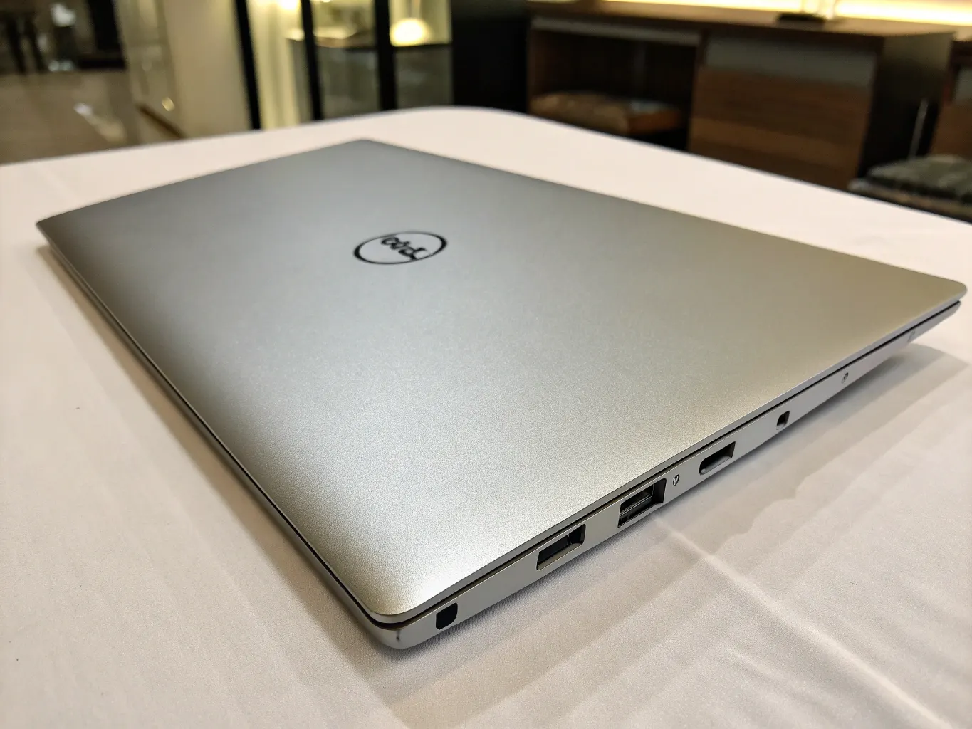 A silver Dell XPS 13 closed on a white table.